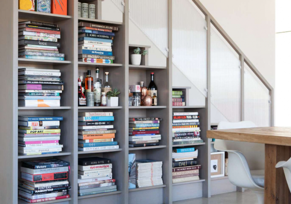 Lemari bawah tangga dengan rak terbuka untuk menampilkan koleksi buku